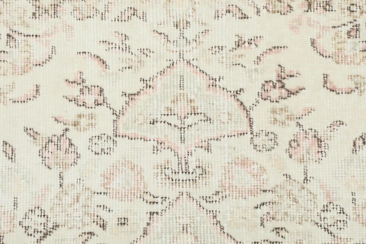 Close-up of the faded floral motifs and intricate patterns within the rug.