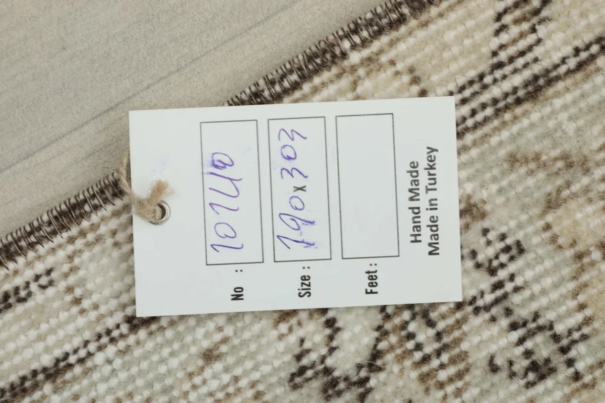 View of the rug's back with a size and origin tag attached, showing hand-knotted construction.