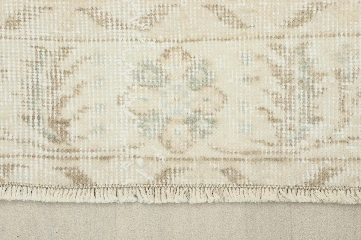Close-up of the rug's border and short fringe, displaying the detailed floral motifs and texture