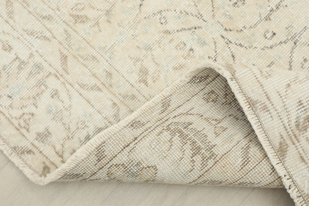 View of the rug folded back to show the reverse side and the cotton foundation