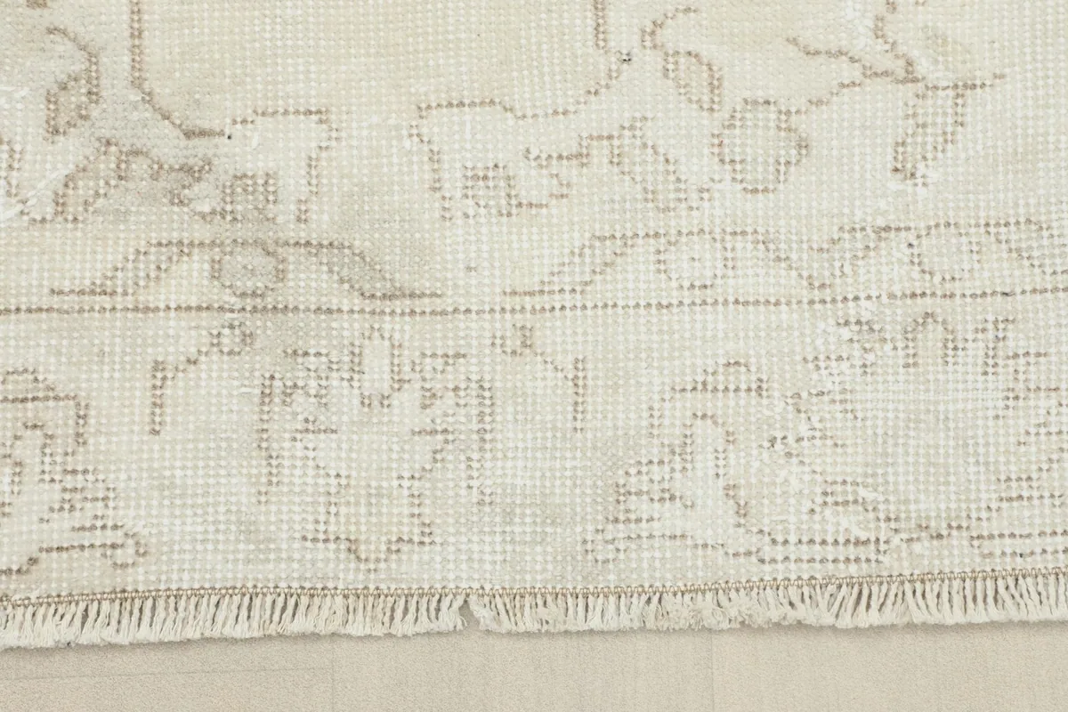 Close-up of the rug's short, natural fringe and the subtle border design along the edge.