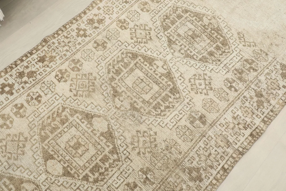 Angled view focusing on the intricate tan geometric motifs against the beige field
