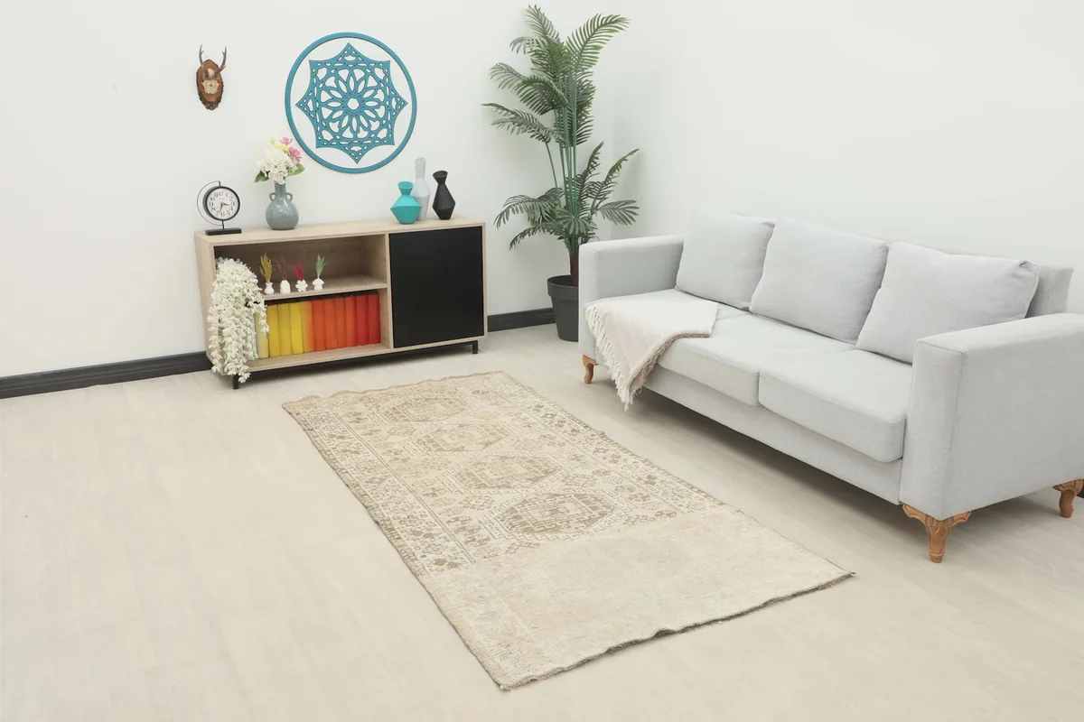 Vintage Anatolian rug displayed in a living room setting, showing its scale next to a sofa