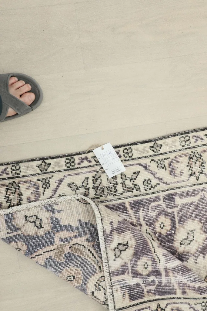 Overhead view of a foot next to the folded rug, with a product tag visible near the border