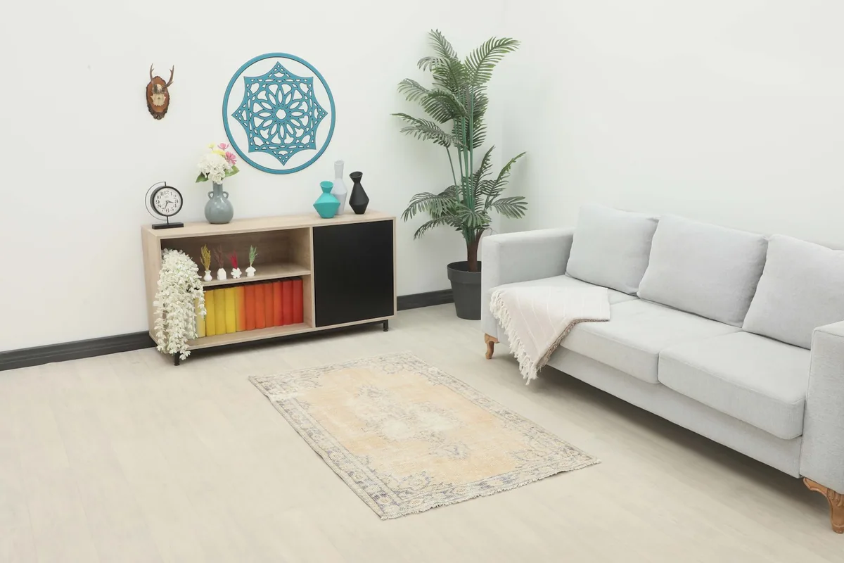 Beige and gray vintage rug placed in a living room setting with a light gray sofa and wooden cabinet
