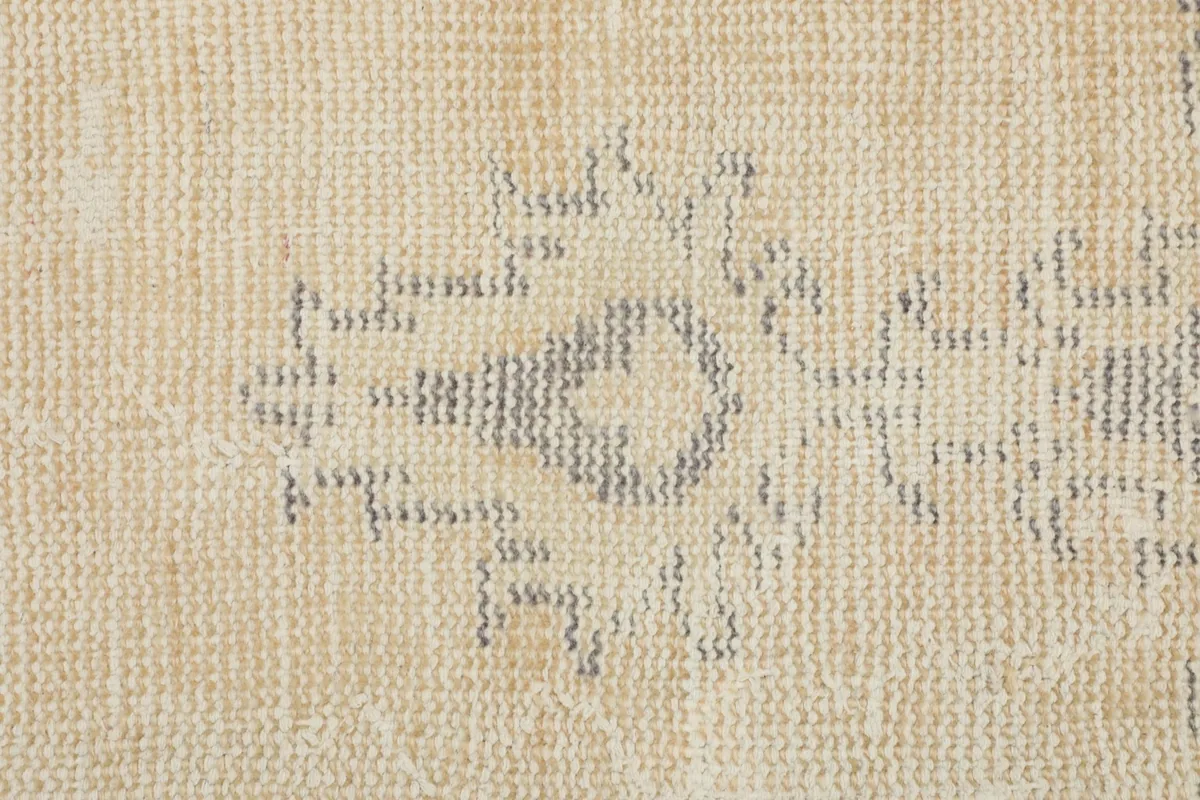 Macro view of the hand-knotted wool pile, showing the texture and detail of the gray patterns on beige