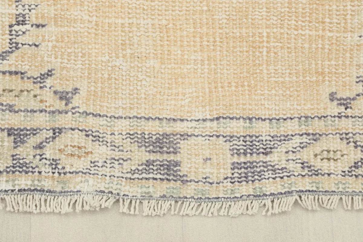 Close-up of the bottom edge of the rug, showing the worn fringe and border design