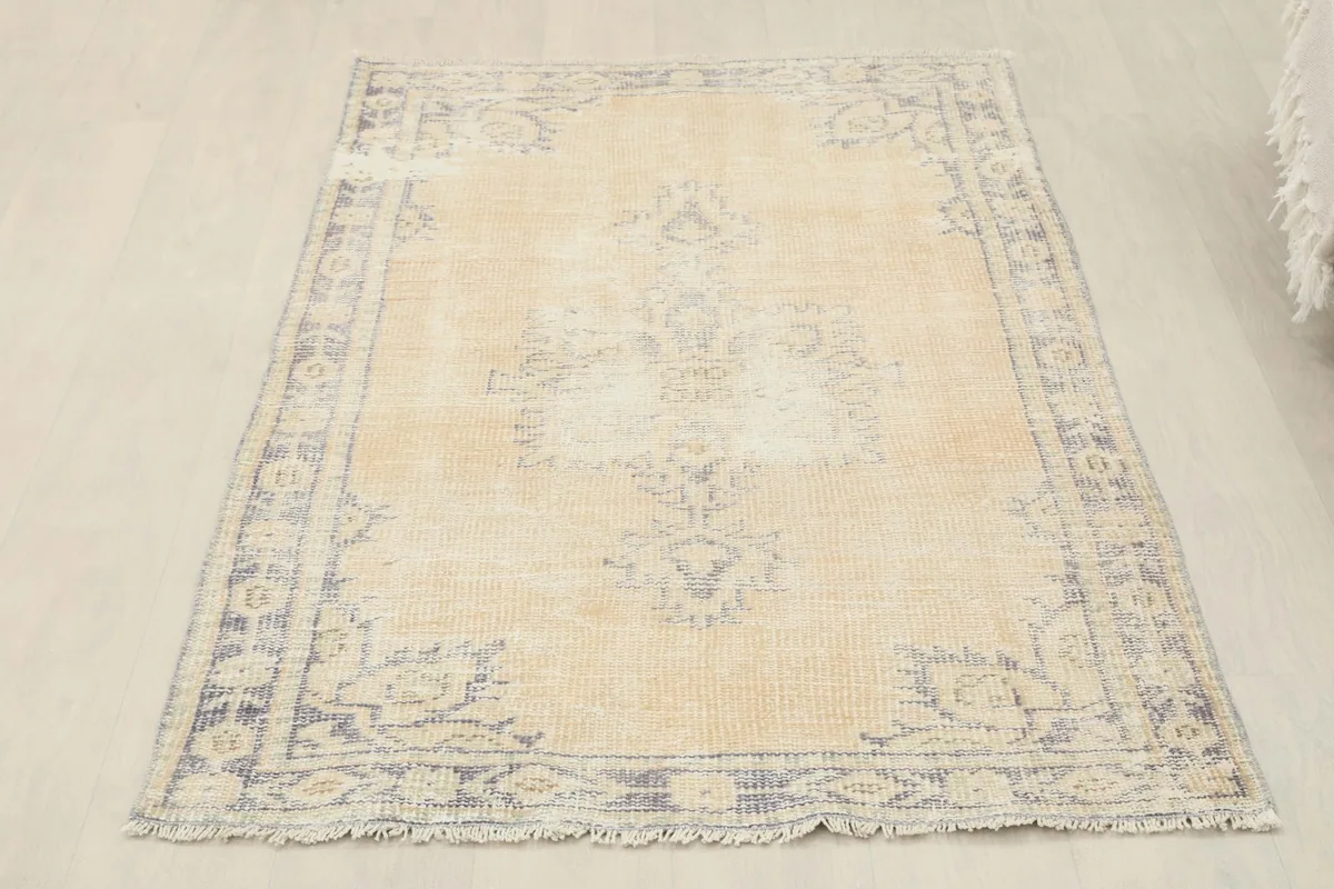 Full overhead view of the beige and gray vintage rug, highlighting its complete design and shape