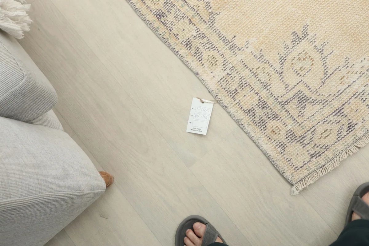 Overhead view showing a foot next to the rug, indicating its mini size in a home setting