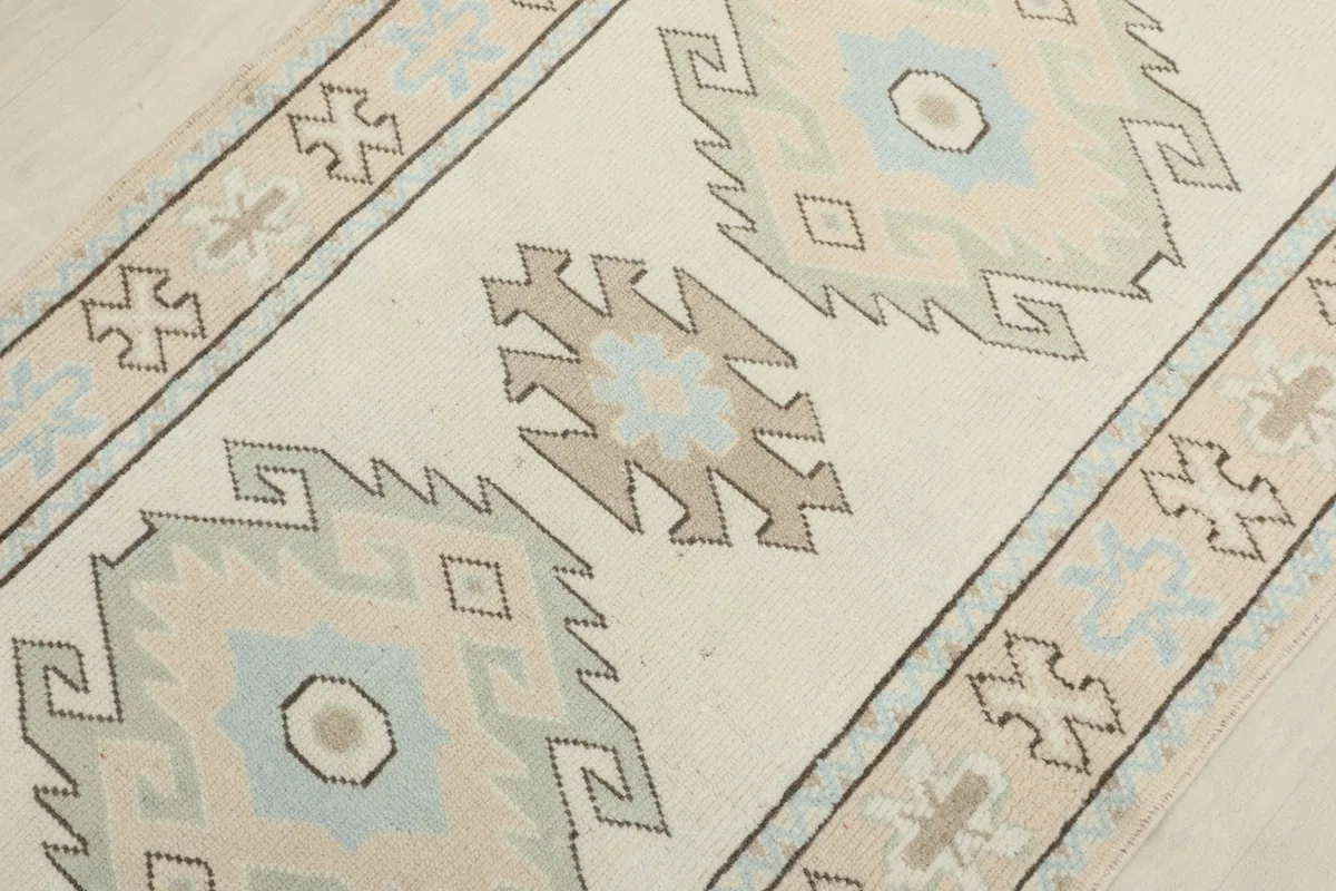 Angled view focusing on the central geometric medallions in blue and tan on the ivory background