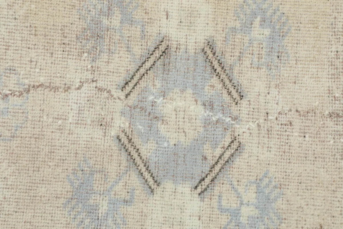 Extreme close-up of a central blue geometric design, showing the hand-knotted wool pile