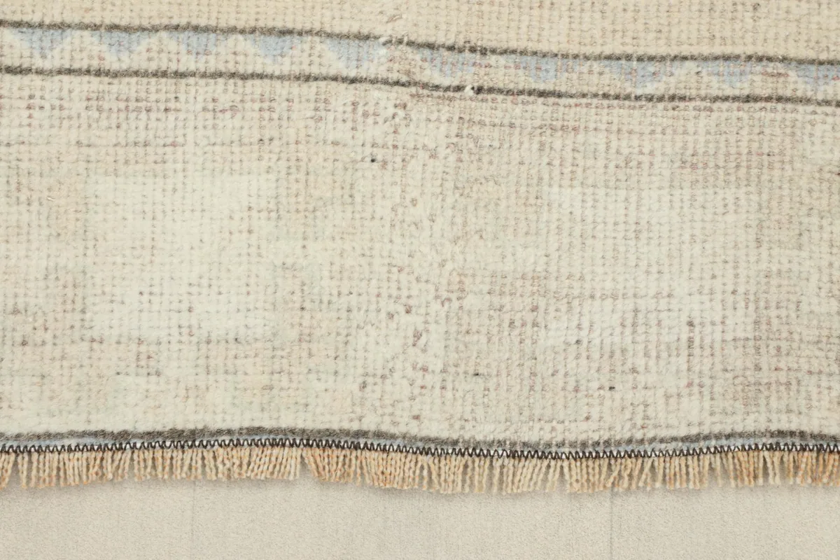Underside view of the rug, revealing the hand-knotted cotton foundation and short fringes
