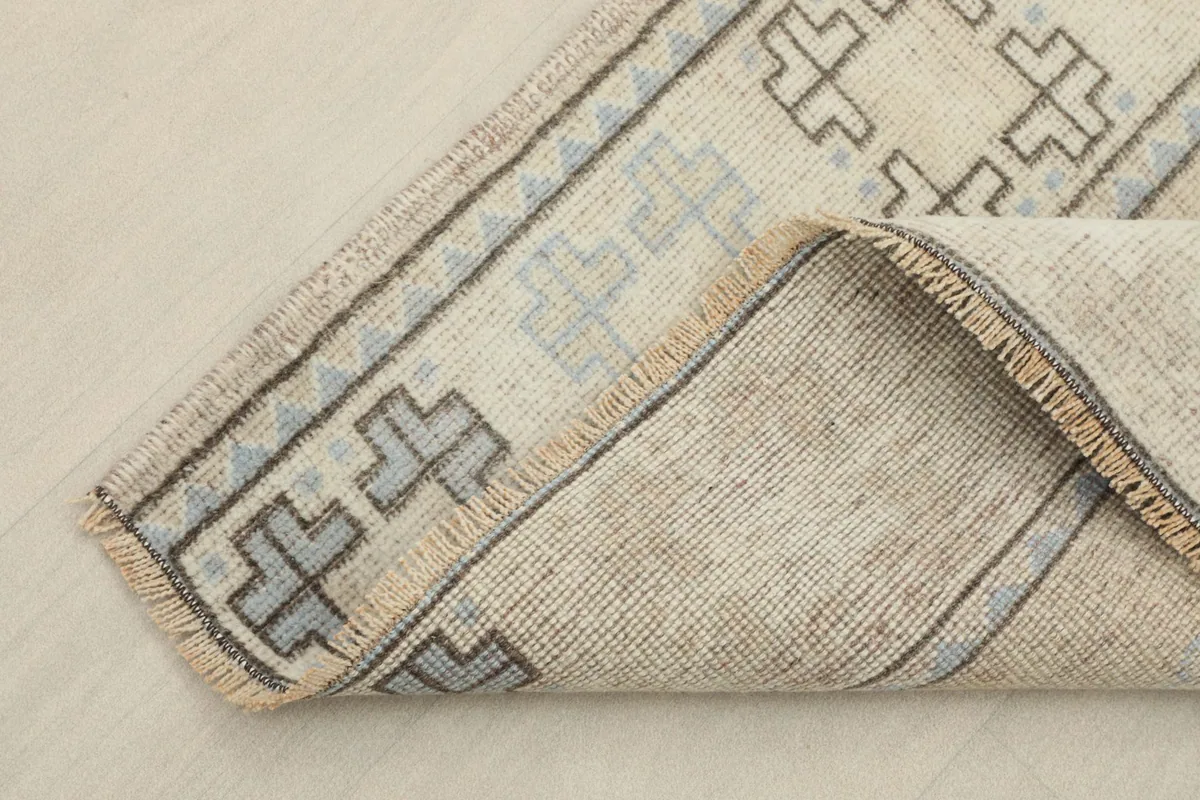 Corner of the rug folded back, showcasing the thickness and construction of the vintage piece