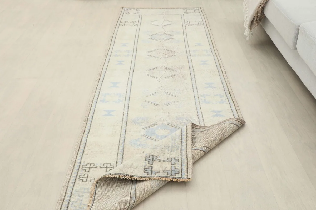 Runner rug with one end partially folded, demonstrating its flexibility and vintage condition