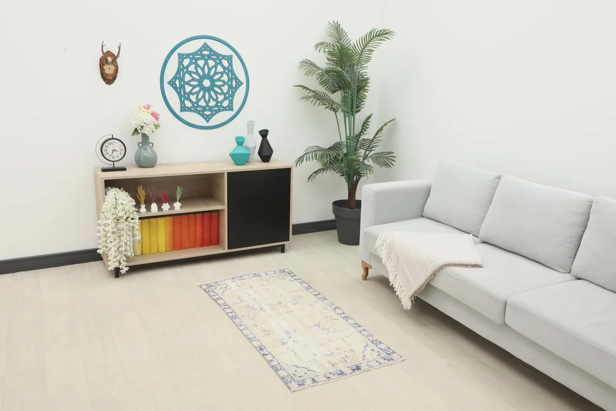 Ivory and navy vintage rug placed in a modern living room setting with a sofa and cabinet.