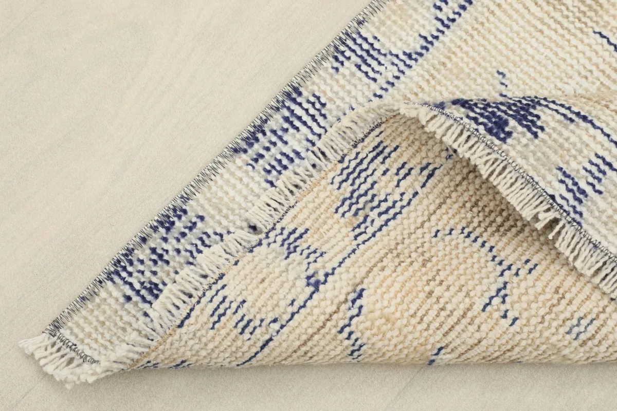 Folded corner of the rug showing the reverse side with the cotton foundation and hand-knotting.