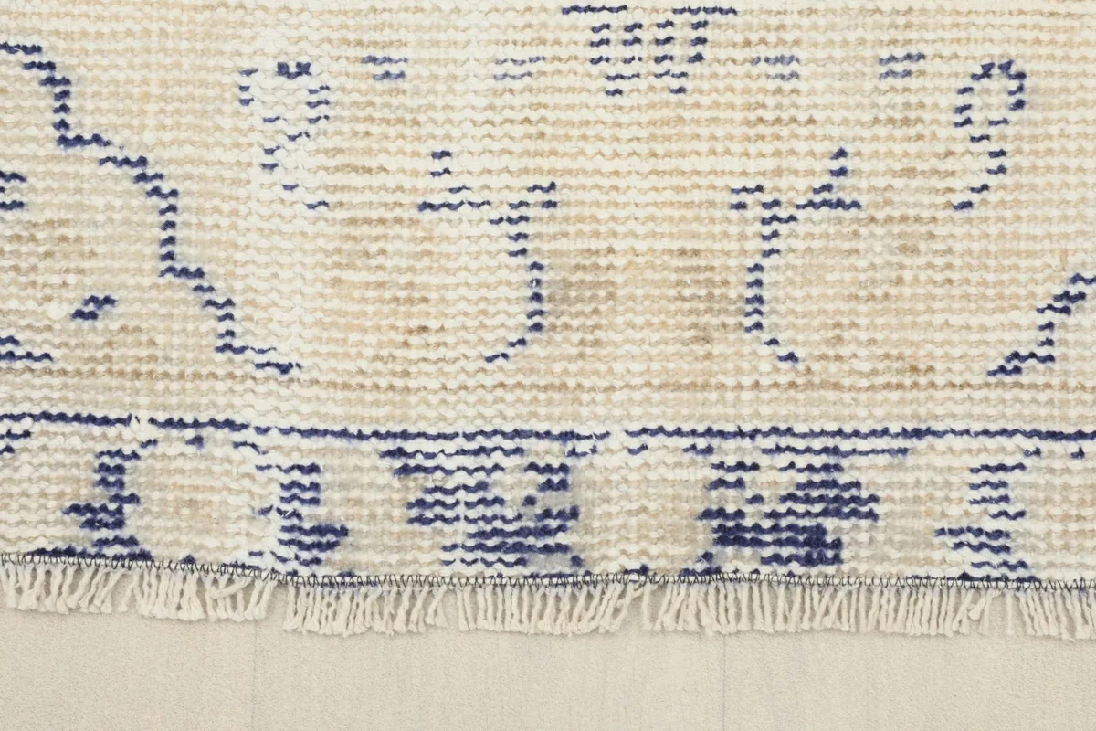 Close-up of the short, aged fringes and the patterned border of the vintage rug.