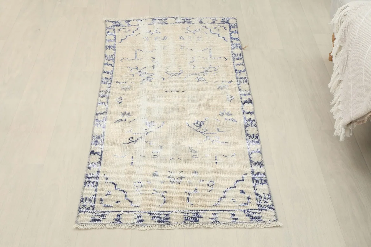 Full overhead view of the ivory and navy vintage Anatolian rug, positioned on a light floor.