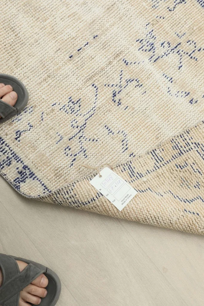 Detail shot of the rug's texture and color variation, with feet in sandals for scale.