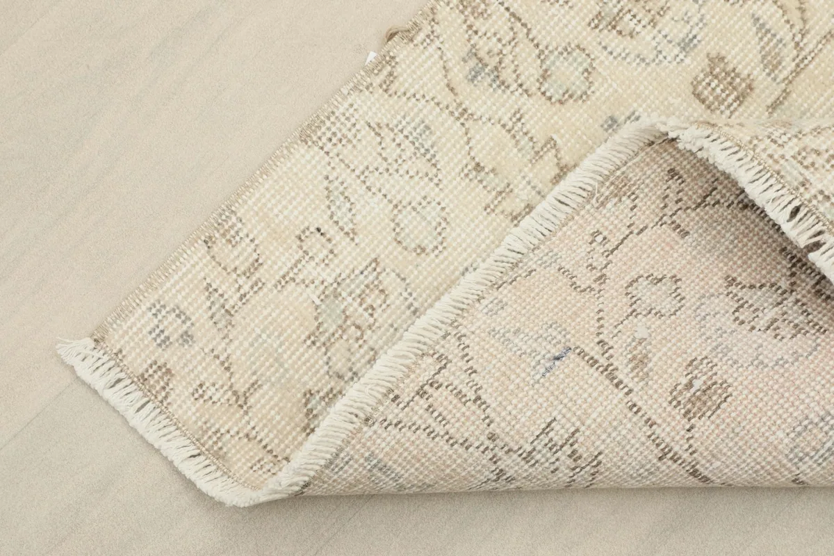 Corner of the rug folded back to show the cotton foundation and reverse side