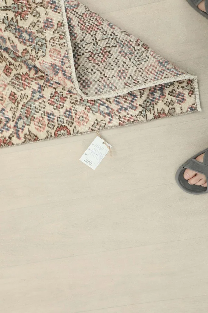 Overhead view with a tag and feet, showing the rug in context on a light floor