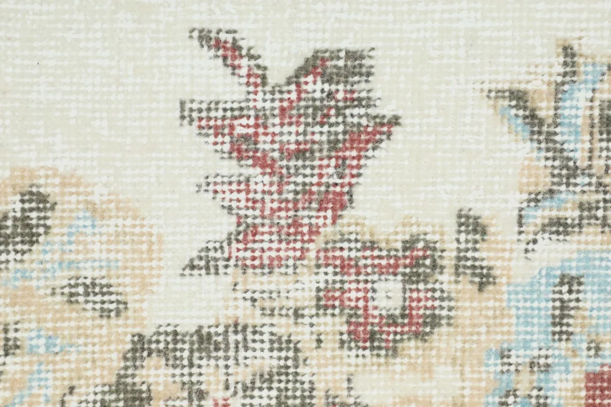 Extreme close-up of the rug's wool pile, showing the texture and faded colors of the floral design.