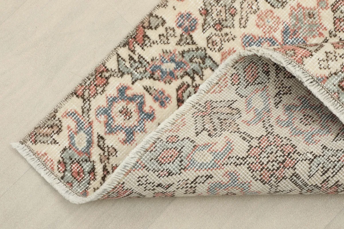 Corner of the rug folded back to show the cotton foundation and reverse side of the knots.
