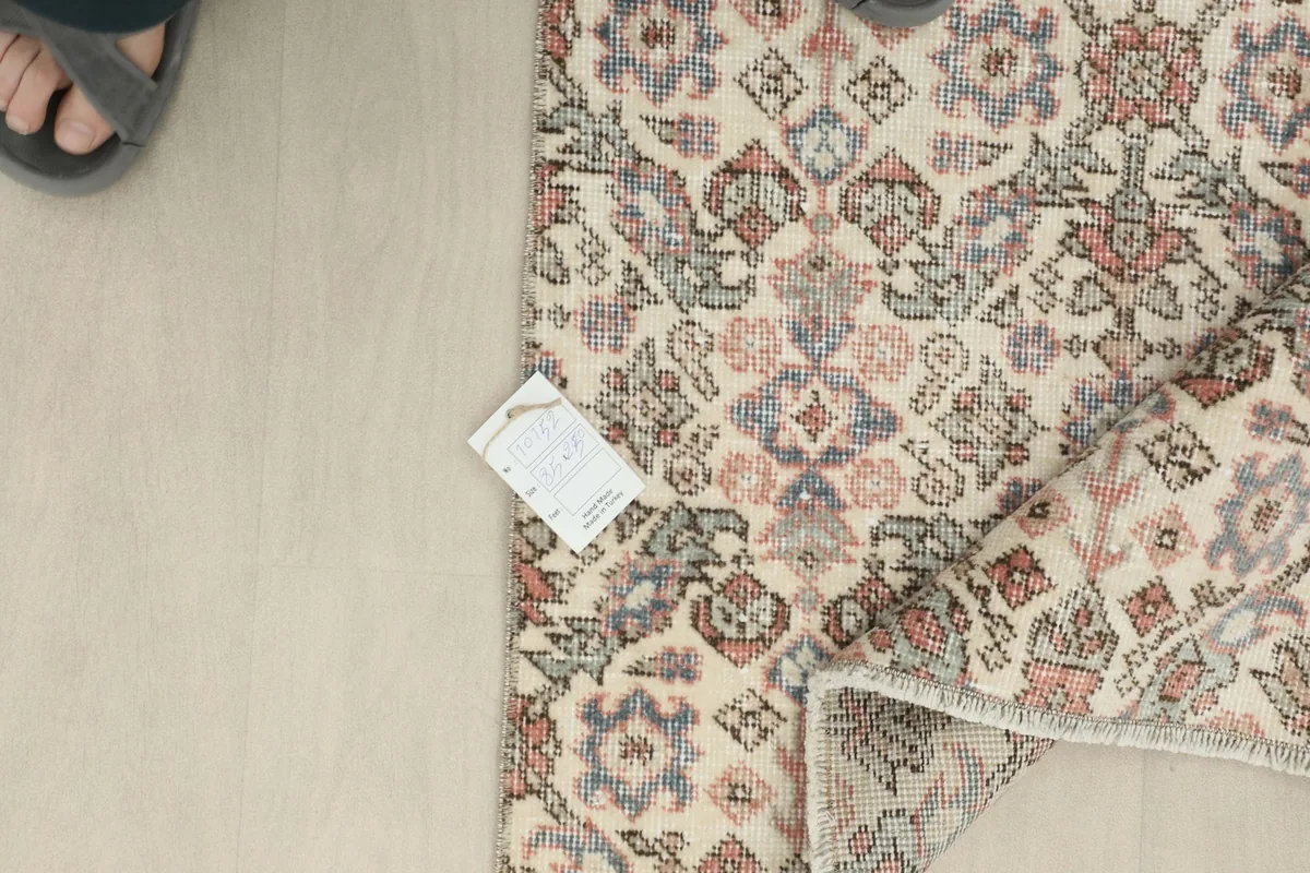 Overhead view showing the rug's corner with a size tag and part of a foot.