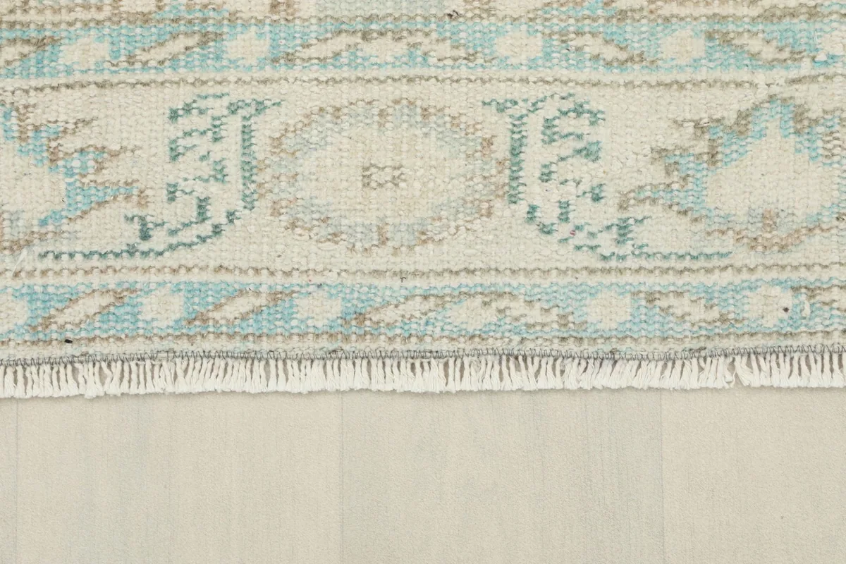 Close-up of the rug's border and fringe, highlighting the blue and beige geometric designs
