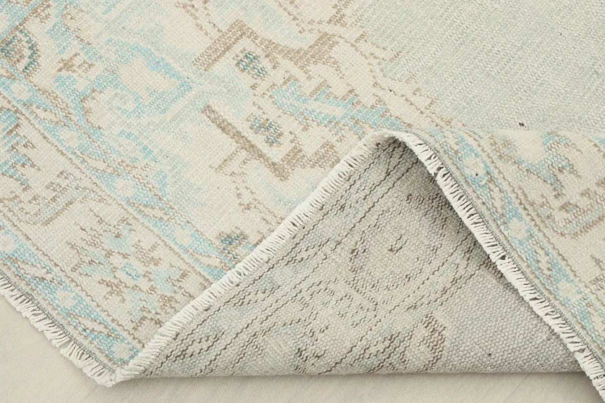Folded corner of the rug, revealing the wool pile and cotton foundation construction