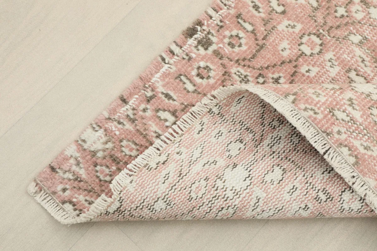 Corner of the rug folded to show the cotton foundation and the reverse side of the hand-knotting