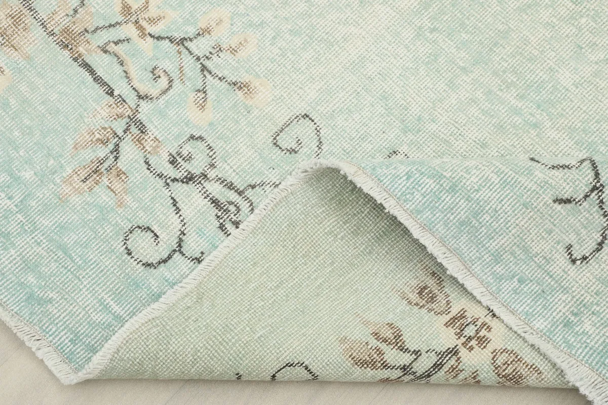 Folded corner showing the back of the rug, revealing the cotton foundation and hand-knotted construction.