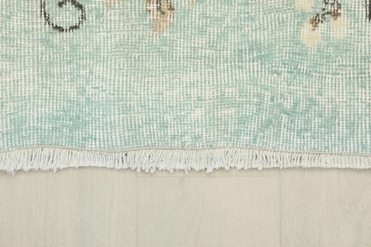 Detail of the short, neatly finished fringe at one end of the hand-knotted wool rug.