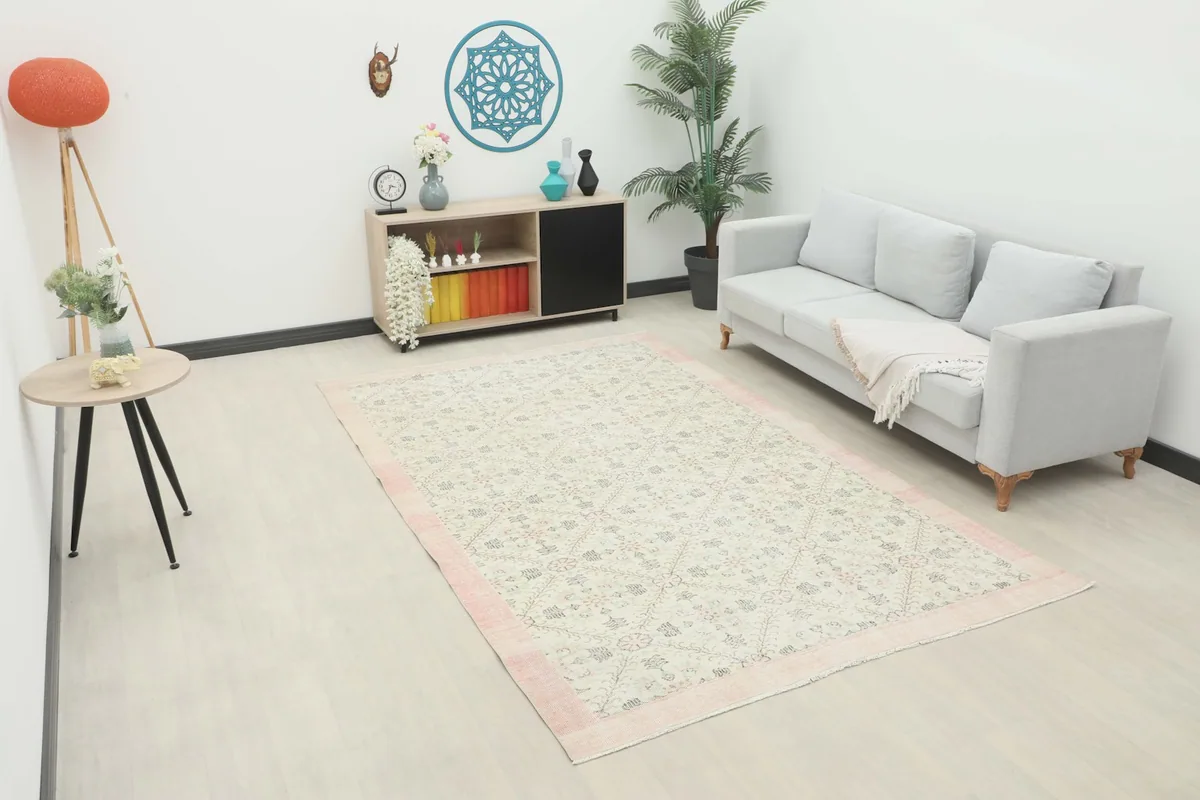 Vintage Anatolian area rug in an ivory and rose palette placed in a modern living room setting
