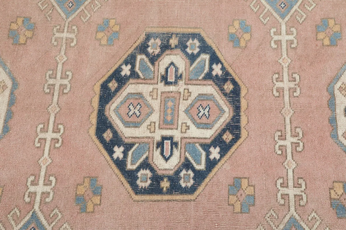 Detailed close-up of the central navy and blue geometric medallion on the rose field.