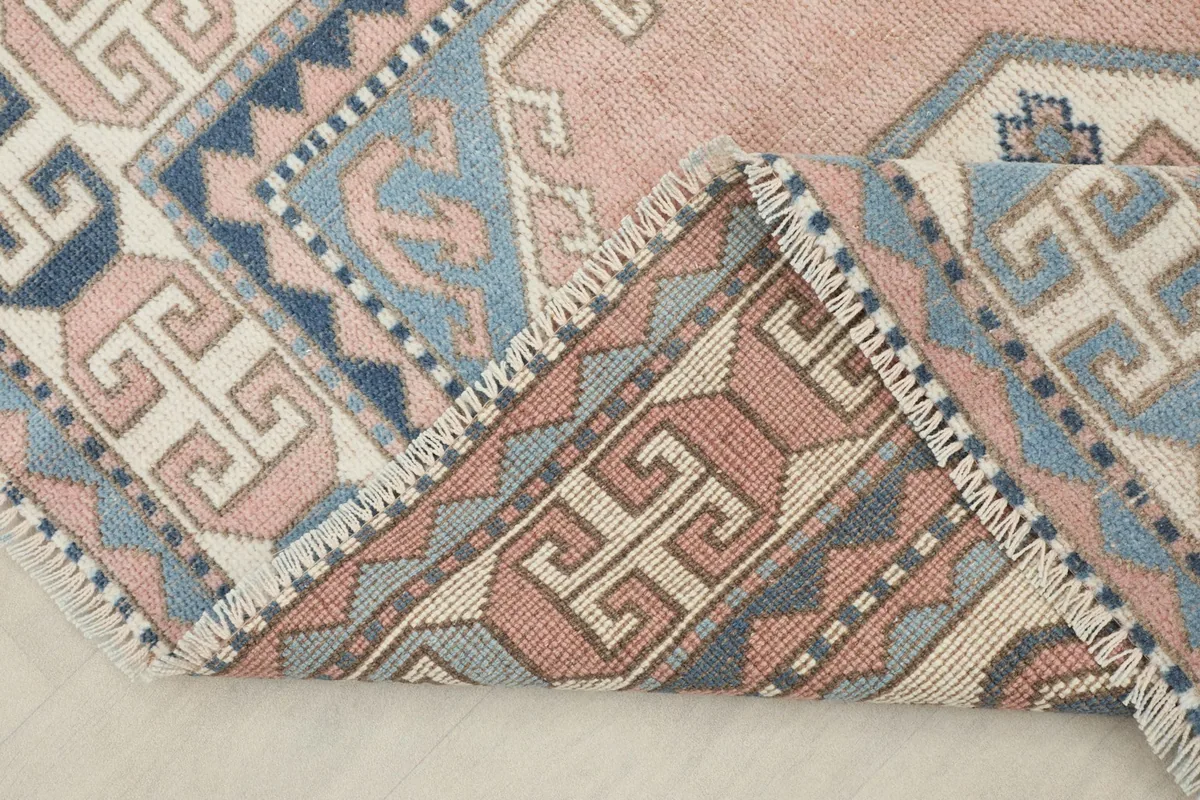 View of the rug folded back, revealing the reverse side and the construction of the hand-knotted wool on cotton.