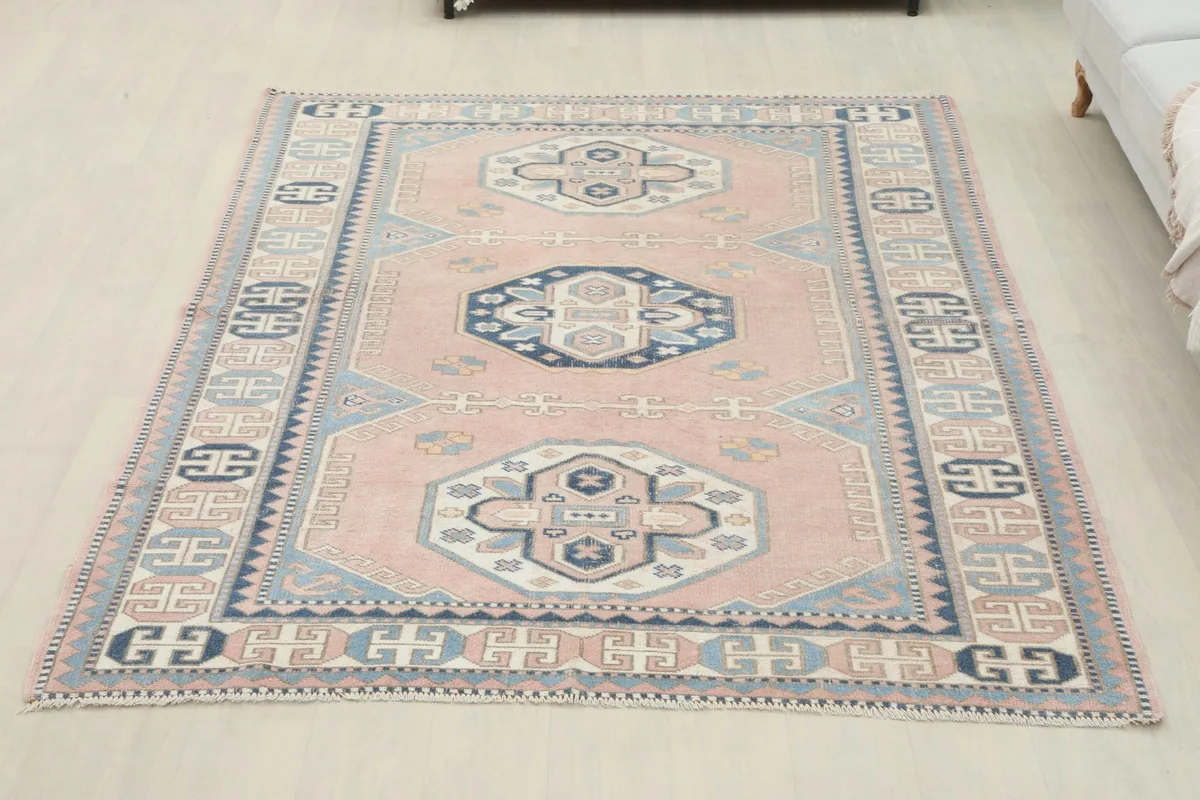 Full overhead view of the vintage rose and navy geometric rug laid out on a light-colored floor.