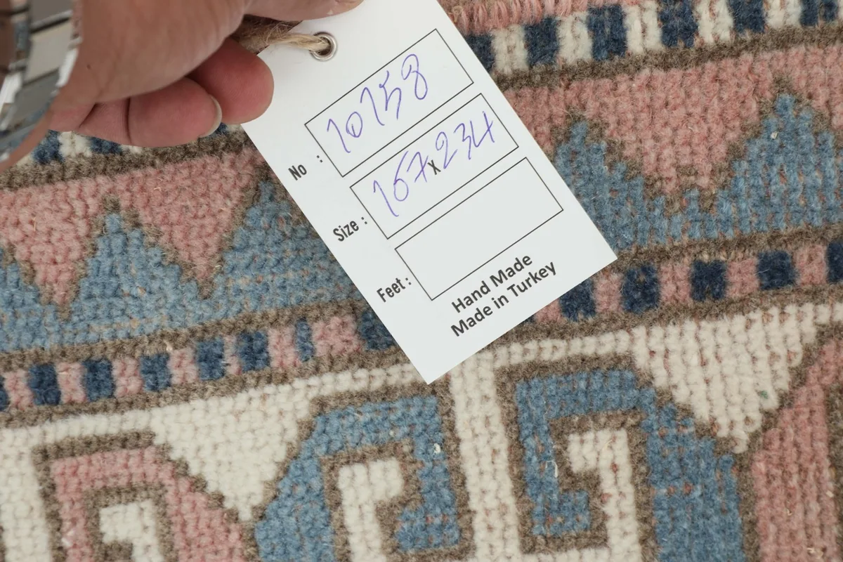 Hand holding a tag indicating the rug's handmade origin in Turkey and its dimensions.