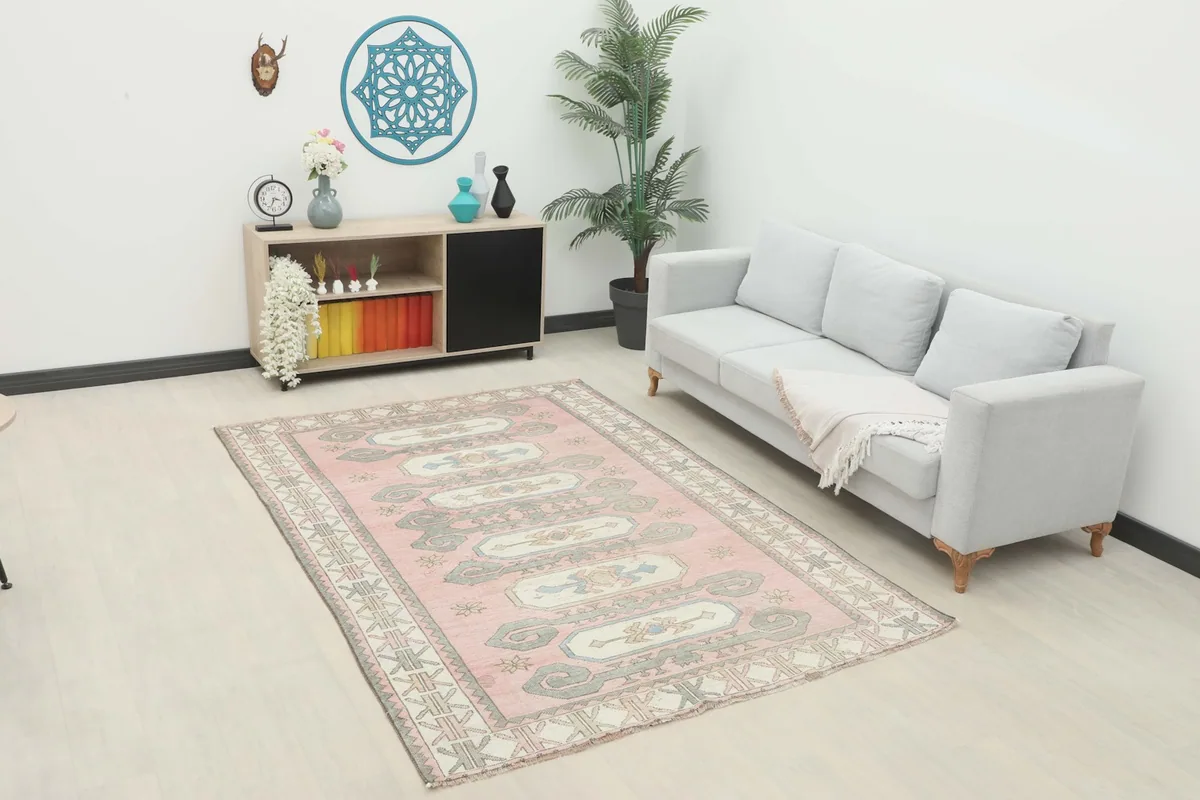 Rose rug displayed in a living room setting with a sofa and side cabinet.