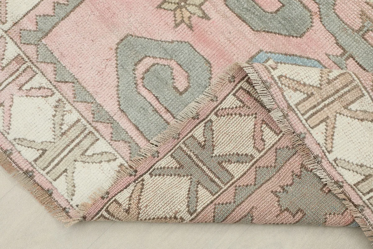 Corner of the rug folded to show the thickness and back of the hand-knotted construction.