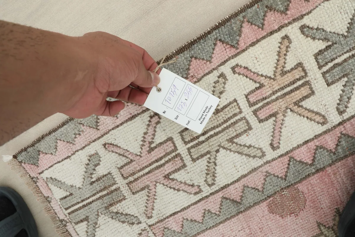 A hand holding the product tag, showing the rug's quality and origin details.
