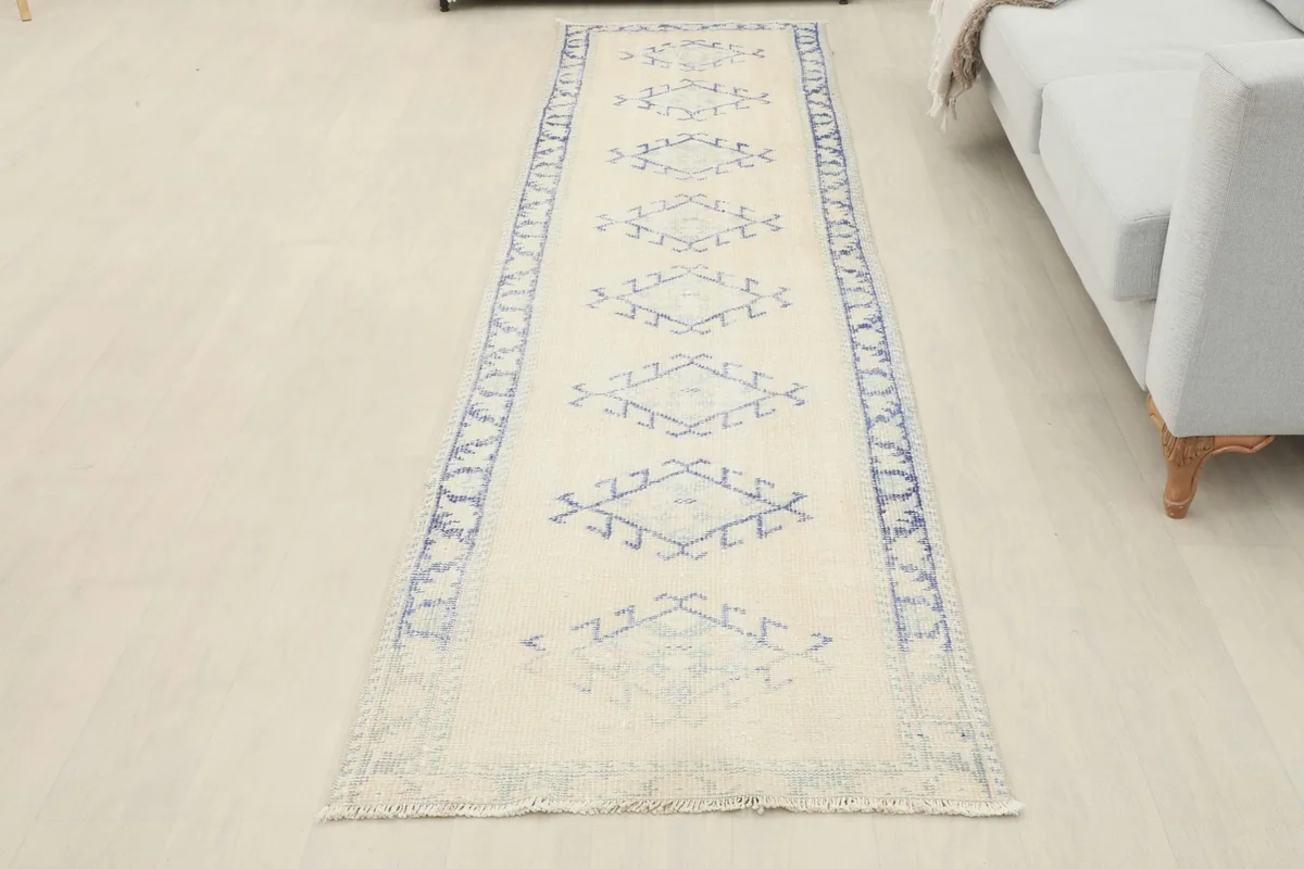 Full view of the ivory and blue runner rug laid out in a room, providing a sense of its overall appearance and length.