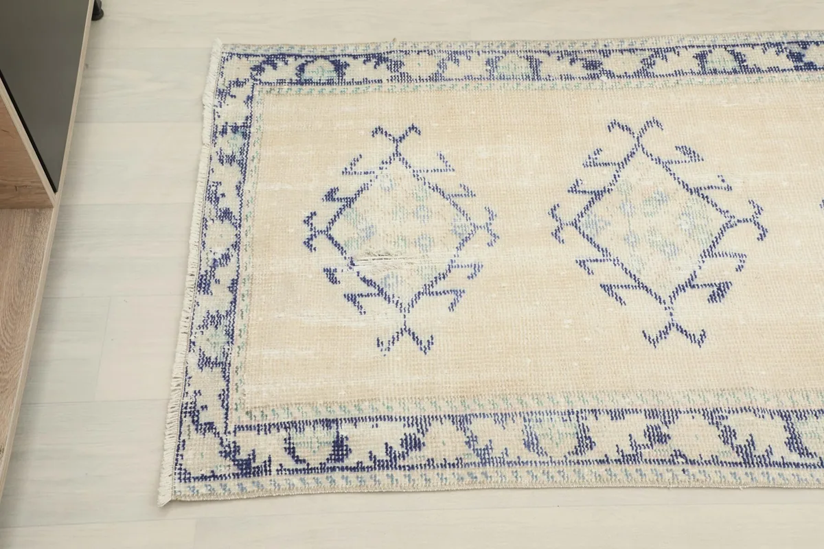 Overhead close-up of the runner rug, highlighting the blue geometric motifs on the ivory field.