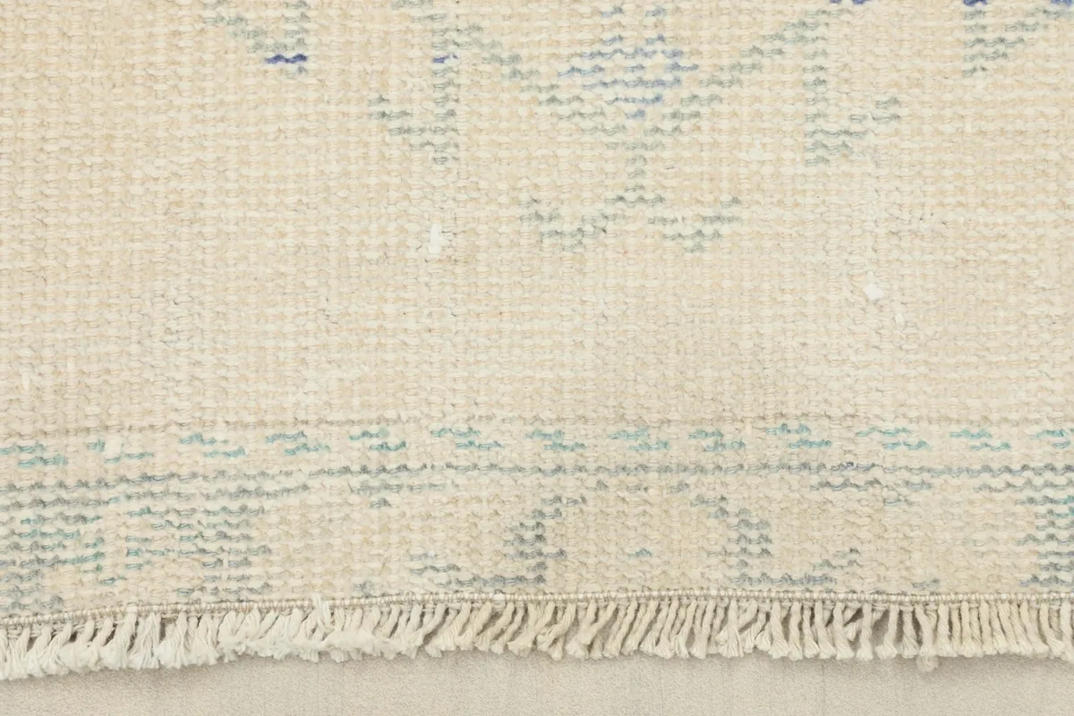 Close-up of the short fringe and the distressed border design at one end of the vintage runner rug.