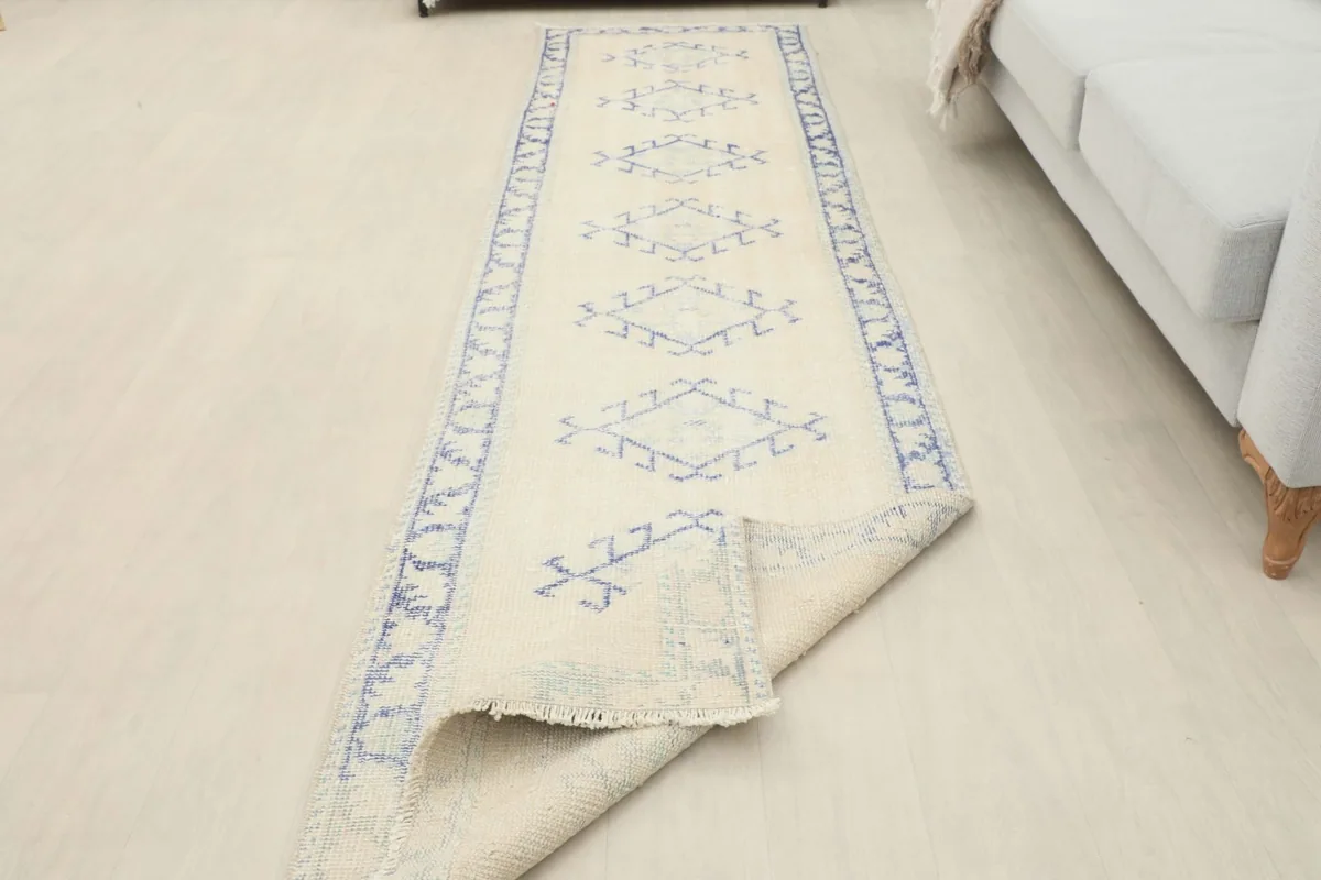 Runner rug partially folded, showcasing its length and flexibility, with the blue patterns visible.