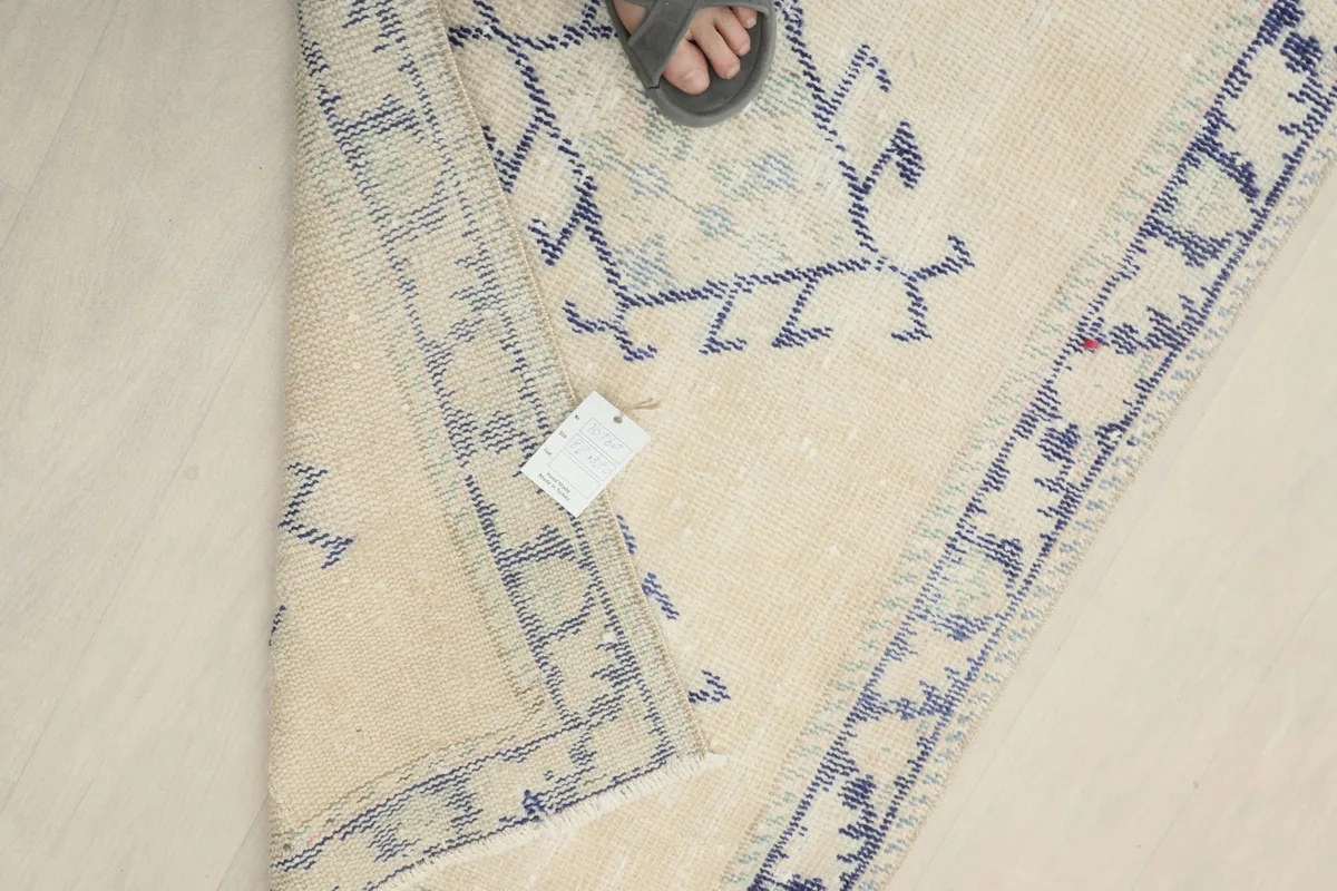 Overhead view showing a foot next to the folded rug, indicating its size and scale in relation to a person.