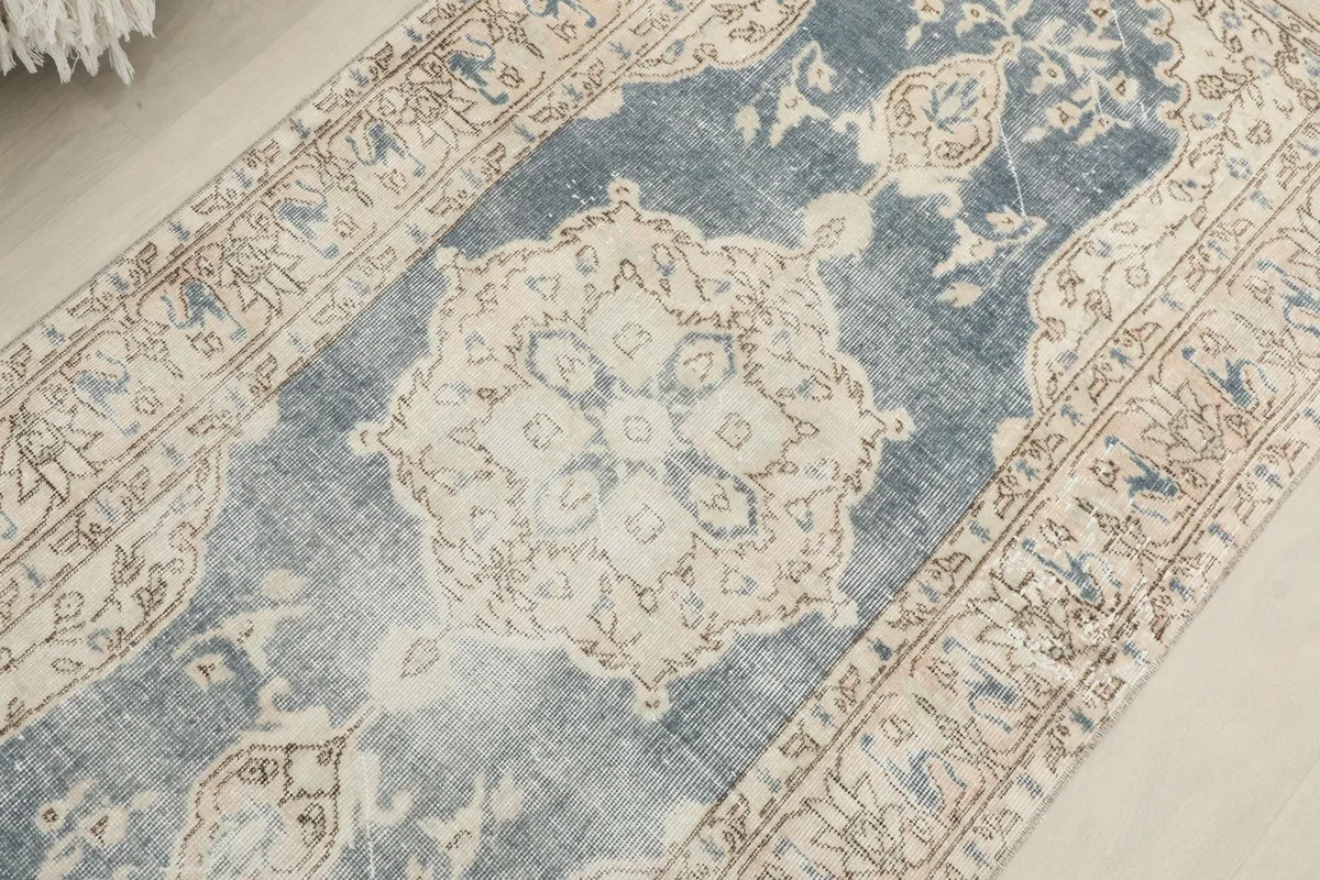 Overhead angled shot focusing on the central ivory medallion and the surrounding blue field of the rug