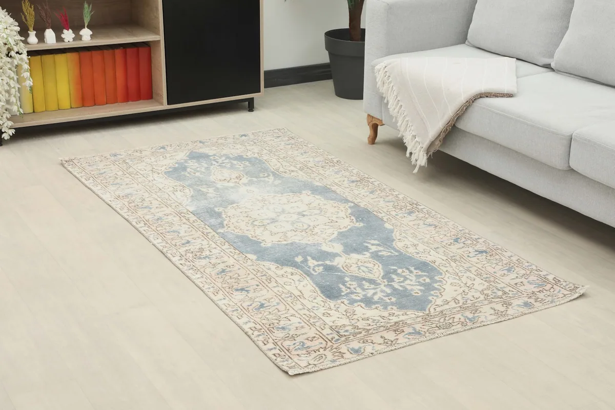 Angled view of the blue and ivory rug in a room, showing its placement in front of a sofa and cabinet