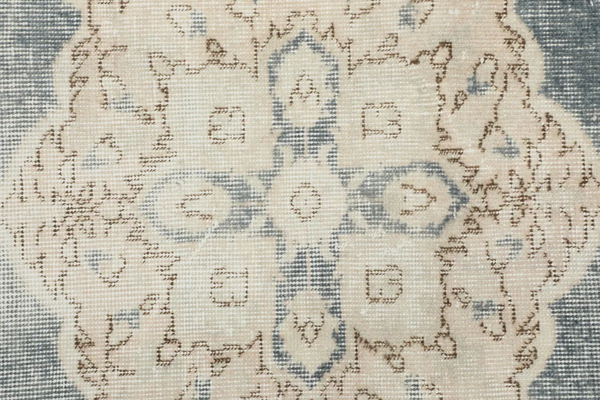 Close-up detail of the central ivory medallion pattern with subtle blue and tan accents