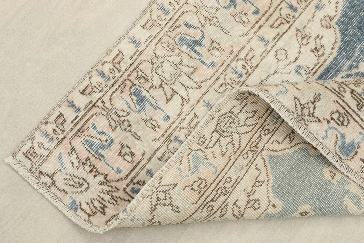 Corner of the rug folded back to reveal the back of the hand-knotted wool pile on cotton foundation